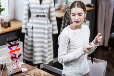 Bileğini kokulu beyaz süveterli gülümseyen güzel uzun saçlı kadın