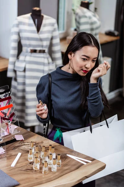 Langharige schattige dame in een witte trui kiezen een parfum — Stockfoto