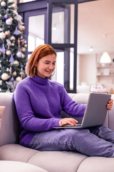 Red-haired pretty smiling girl in a violet sweater looking involved — Stock Photo, Image
