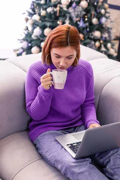 Ganska ung strålande flicka i en lila tröja dricka kaffe — Stockfoto