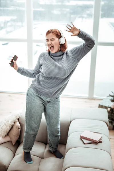 Egy szürke pulóver, boldog érzés sugárzó fiatal vörös hajú lány — Stock Fotó