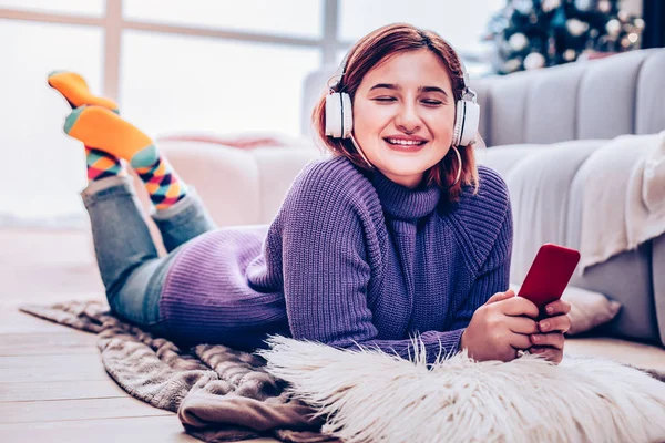 Jovem de cabelos vermelhos radiante menina em fones de ouvido relaxante em casa — Fotografia de Stock