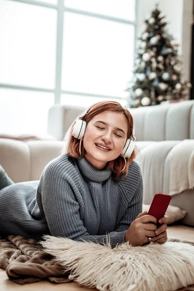 Joven chica pelirroja radiante en auriculares disfrutando de la música —  Fotos de Stock