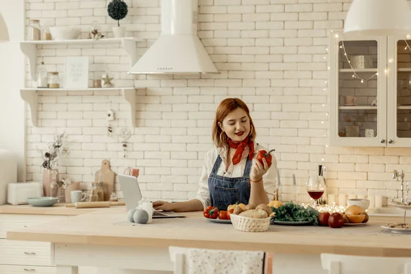 Beautiful young red-haired girl with big earrings holding a red pepper in her hand — Stock Photo, Image