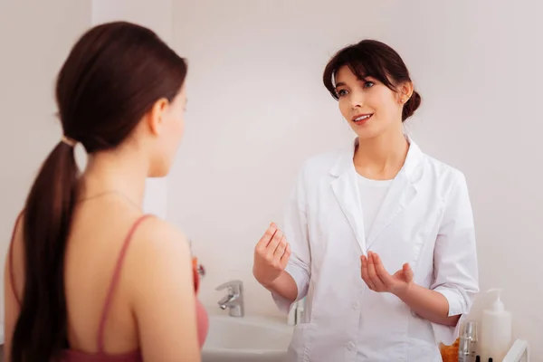 Jovem simpática conversando com seu cliente — Fotografia de Stock