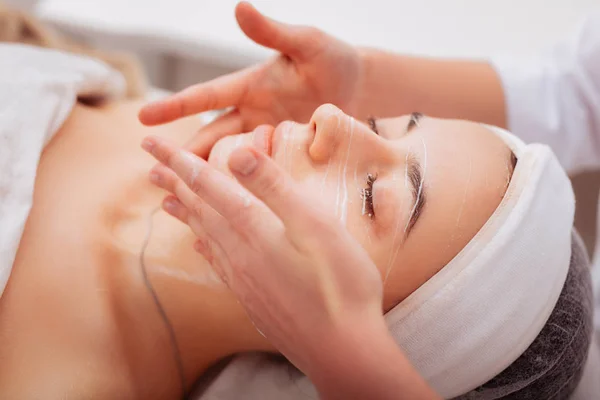 Professional nice cosmetologist applying cream on the face — Stock Photo, Image