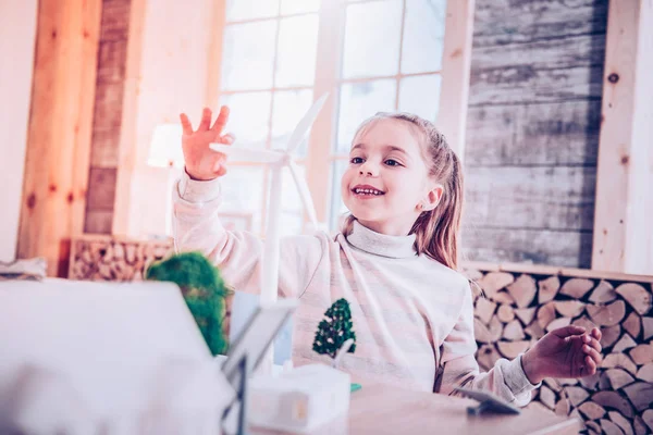 Cheerful young lady touching toy small windmill — Stock Photo, Image