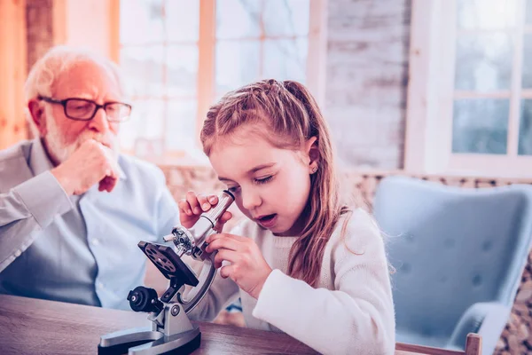 Estudiante inteligente con bonito peinado usando microscopio —  Fotos de Stock