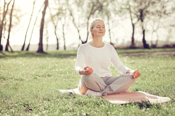 Relaxed mature woman doing yoga in park — Stock Photo, Image