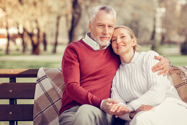 Handsome bearded male person embracing his wife