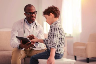 Bir tablet kullanarak doktor semptomları açıklayan çocuk