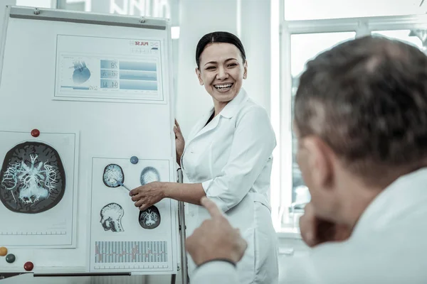 Улыбающаяся женщина-врач показывает рентгеновские снимки мозга — стоковое фото