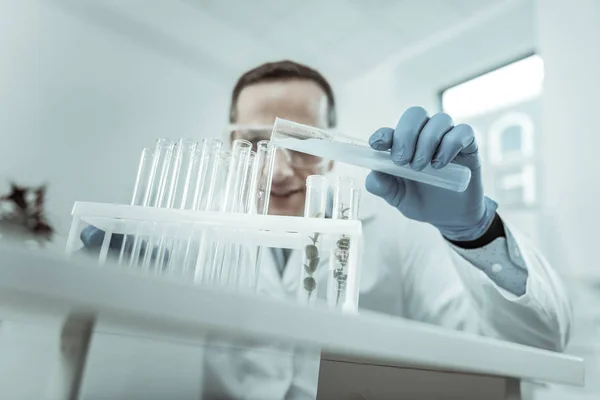 Scientist in clear glasses filling all empty tubes against him — Stock Photo, Image