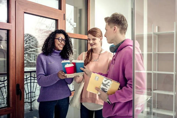 Estudiantes con sudaderas coloridas hablando y tomando café — Foto de Stock