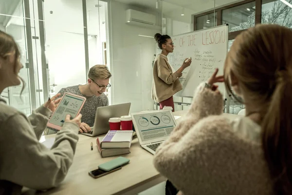 Tres estudiantes modernos que utilizan sus aparatos durante la clase —  Fotos de Stock