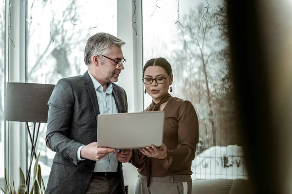 Großer, grauhaariger, gutaussehender Mann in dunkler Jacke und seine Partnerin sehen interessiert aus — Stockfoto