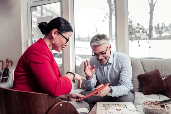 Hombre de negocios adulto de pelo gris con gafas que habla con una mujer con una chaqueta roja — Foto de Stock