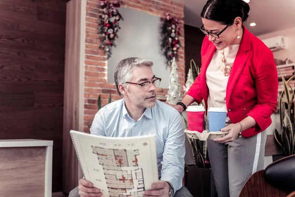 Elegante Geschäftsfrau in roter Jacke bietet ihrem Kollegen Kaffee an — Stockfoto
