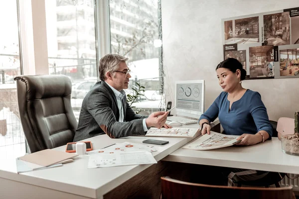 Brunette élégante femme d'affaires avec une longue boucle d'oreille parler à un collègue dans le bureau — Photo