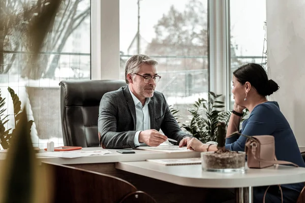 Homme sérieux aux cheveux gris en lunettes parlant de problèmes d'affaires avec son collègue — Photo