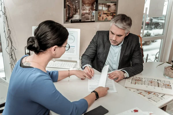 Gris sérieux beau homme aux lunettes apposant sa signature sur le document — Photo