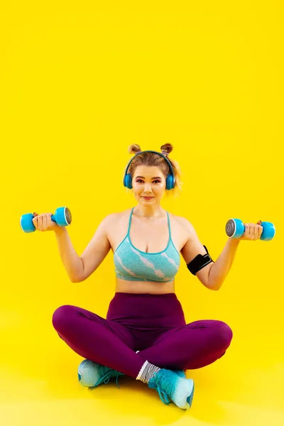 Mujer joven escuchando música en auriculares y haciendo ejercicio — Foto de Stock