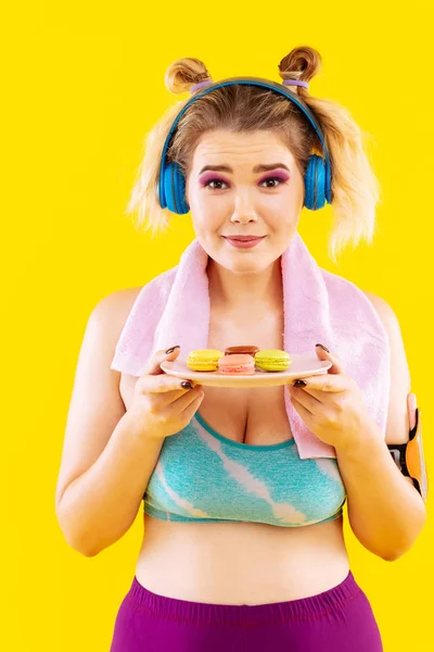 Mujer perdiendo peso sintiéndose incómoda mirando macarons — Foto de Stock