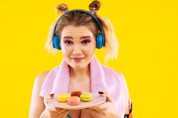 Kvinna med ljusa ögon nyanser håller plattan med söta macarons — Stockfoto