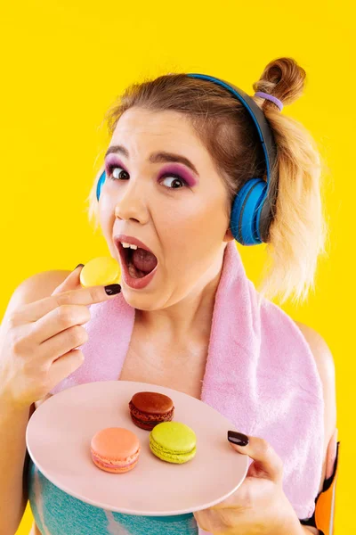 Vrouw die zelf niet de controle na gym terwijl het eten van macaron — Stockfoto