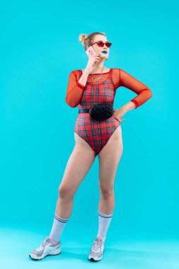 Elbise ve spor ayakkabı. Kırmızı gömlek ve arkadaşına spor ayakkabı giyen genç olağanüstü kadın