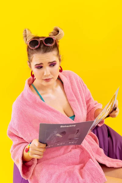 Femme aux lunettes roses se sentant magazine de lecture émotionnelle — Photo