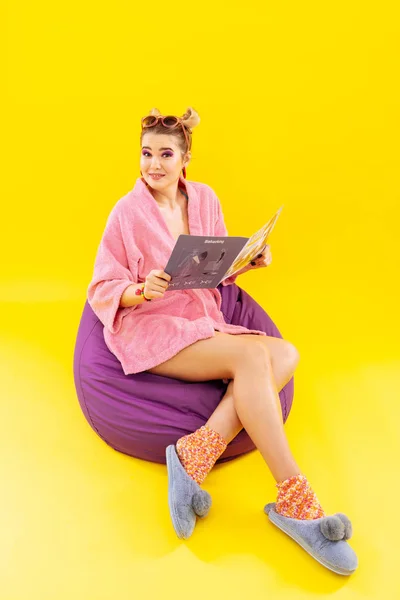 Молодая женщина в домашней одежде читает модный журнал — стоковое фото