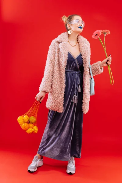 Mulher na moda voltando para casa com saco de frutas e flores — Fotografia de Stock