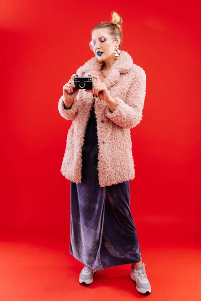 Mulher magro vestindo vestido e casaco rosa segurando câmera de fotos — Fotografia de Stock