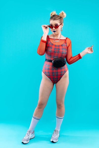 Slim model wearing red bodysuit and black waist bag posing