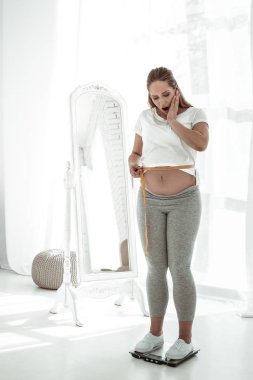 Ölçüm bandı ve ağırlıkları kullanarak uzun saçlı hamile kadın