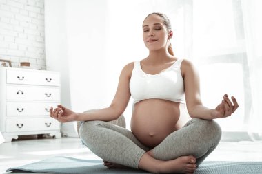 Beyaz üst ve gri tozluk sakin hamile kadın