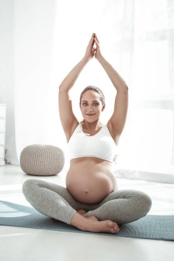 Çapraz ayaklı oturan çıplak mide ile hoş güzel kadın