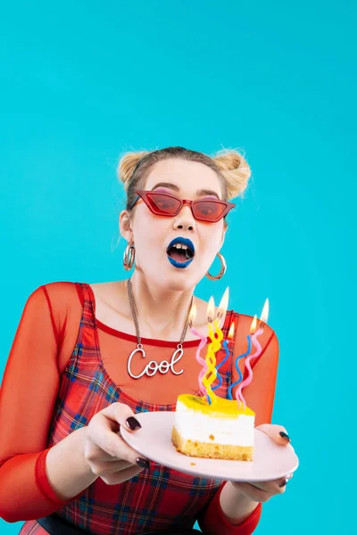 Young woman blowing candles on her yummy birthday cake