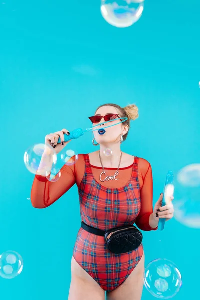 Chica con traje de cuerpo rojo brillante jugando con burbujas de jabón — Foto de Stock