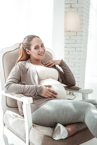 Fröhliche junge Frau mit langem Pferdeschwanz ist schwanger — Stockfoto