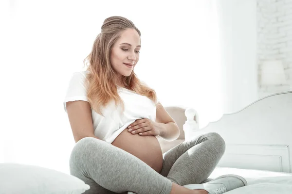 Tranquil light-haired expectant woman measuring size of round stomach — Stock Photo, Image