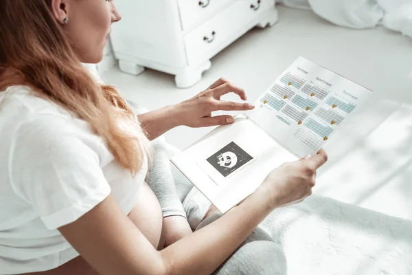 Dyrbara gravid kvinna i vit t-shirt kontrollera gestationsålder — Stockfoto