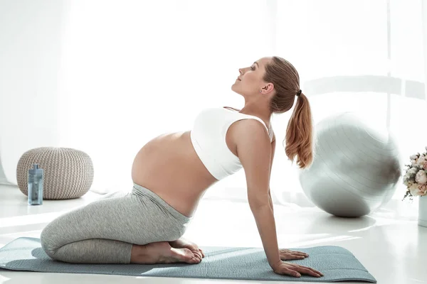 Active long-haired woman with ponytail arching her back during yoga — Stock Photo, Image