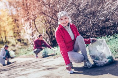 Park temizlerken torbaya plastik şişe koyarak kadın