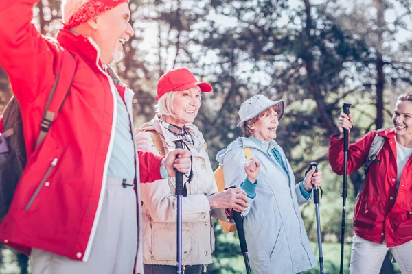 Active retired people fond of Nordic walking resting in forest