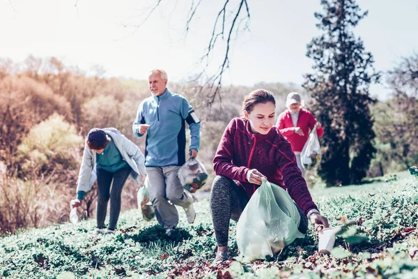 Kvinna som bär sportkläder samla sopor i plastpåse — Stockfoto