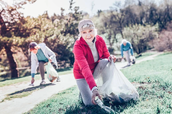 Trevlig tilltalande pensionerad kvinna rengöring parken i helgen — Stockfoto