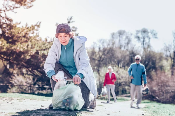 Agradable mujer jubilada con gorra mientras limpia el parque — Foto de Stock