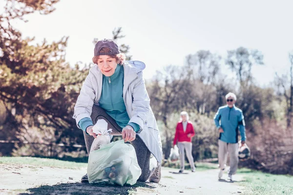 Kadın parkta temizlik kadın yardım plastik torba ile gelecek — Stok fotoğraf
